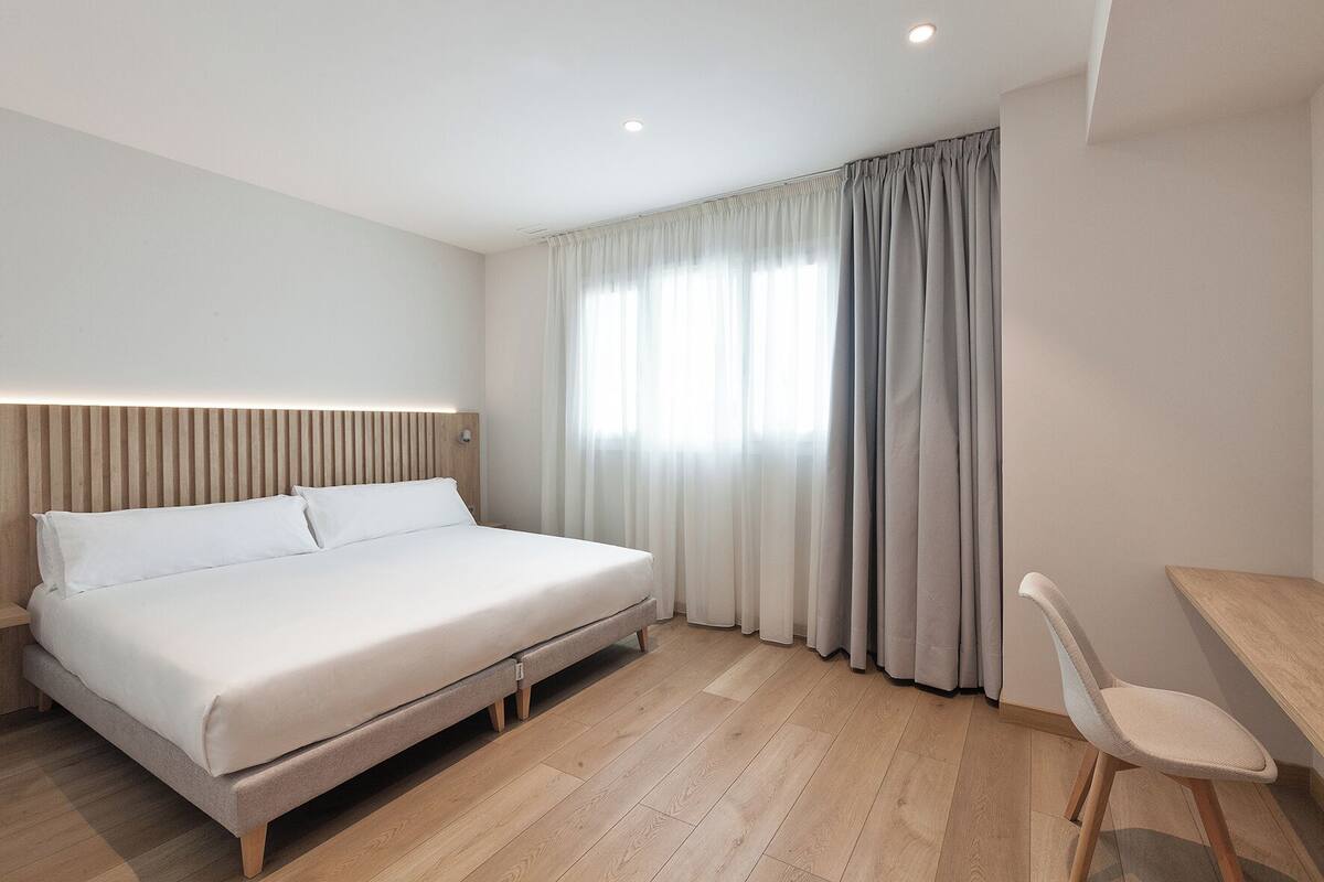 Una habitación de hotel moderna con una cama, un escritorio y una silla.
