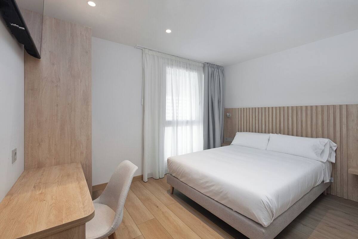 Un dormitorio con una cama, un escritorio y una silla.