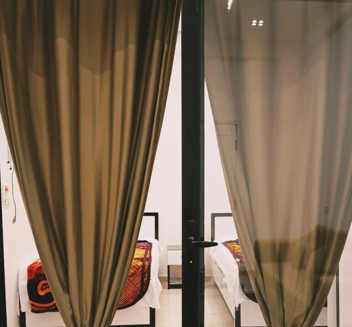 A room with a bed, a chair, and a curtain.