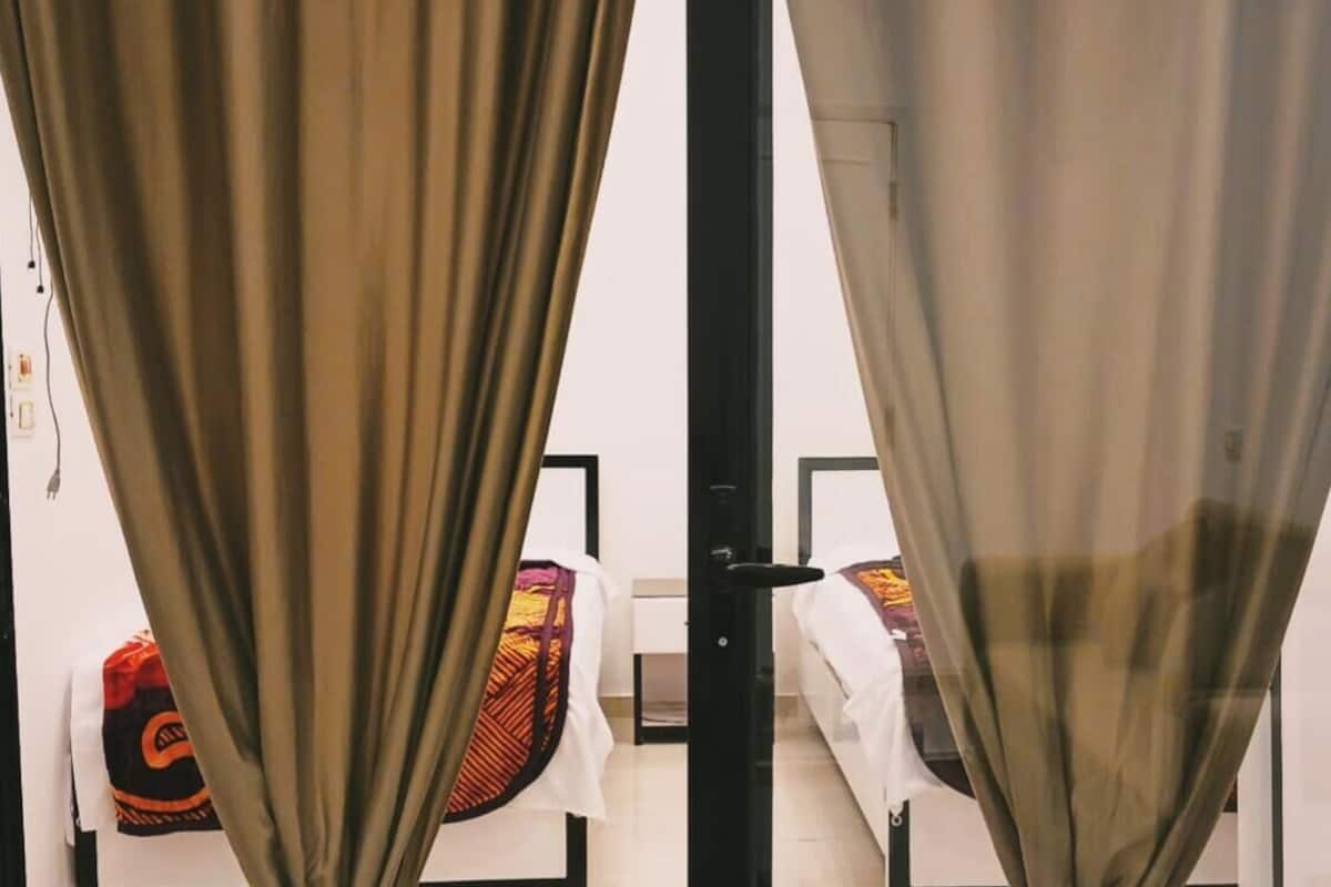 A room with a bed, a chair, and a curtain.