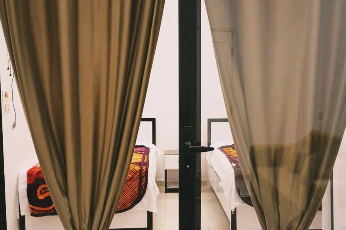A room with a bed, a chair, and a curtain.
