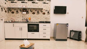 A modern kitchen with white cabinets, a built-in oven, a refrigerator, and a flat-screen TV mounted on the wall. - NOOR SEEN HOUSE  (Luxor)