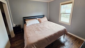 A bedroom with a bed, a nightstand, a window, and a ceiling fan.
