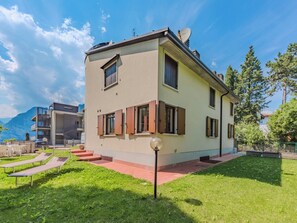 A two-story building with a balcony, a satellite dish, and a small garden with a lawn and a lamp post. - Le Busatte by Interhome (Torbole)