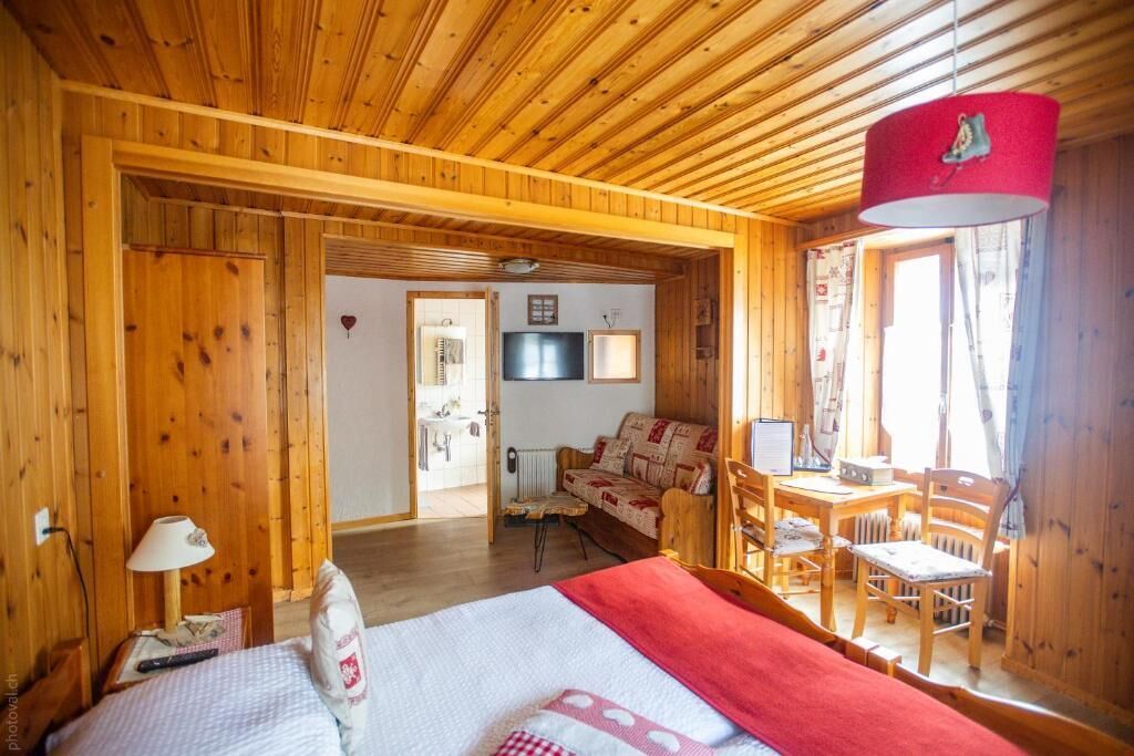 L’intérieur d’un chalet en bois comprend un lit, un canapé, une table à manger et un téléviseur.