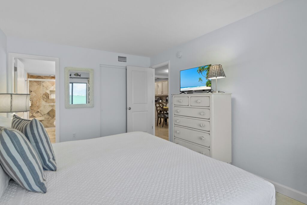 Une chambre à coucher avec un lit, une commode, un téléviseur et une lampe.