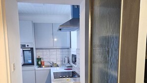 Et kompakt køkken med hvide skabe, en komfur og en mikrobølgeovn.