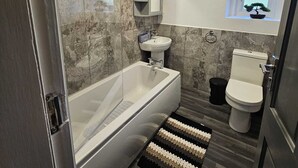 Et moderne badeværelse med badekar, håndvask og toilet.