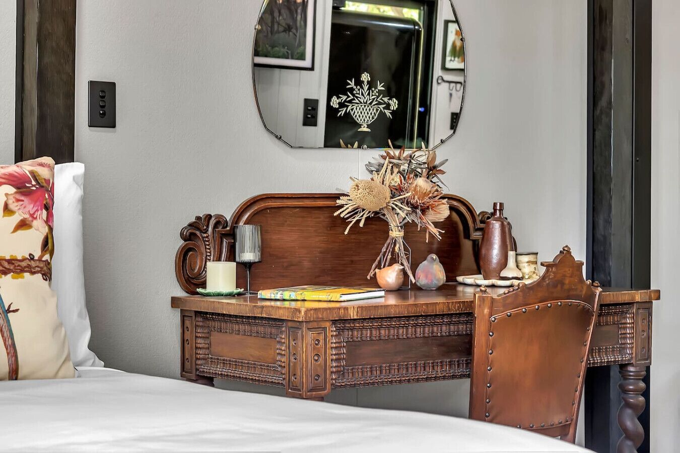 A bedroom with a wooden dresser, a mirror, and a bed with floral bedding.