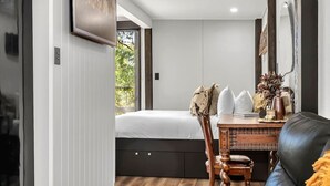 Une chambre à coucher comprenant un lit, une commode en bois, une chaise et une table agrémentée d’objets décoratifs.