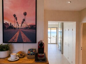 A hallway with a coffee machine, a bowl of fruit, and a potted plant. - Magnifique vue sur le port (Villeneuve-Loubet)