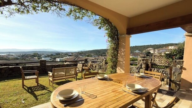 An outdoor dining area with a wooden table and chairs, surrounded by stone walls and greenery. - Pittulongu Horizon - Where Blue Meets Relaxation (Olbia)