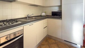 A kitchen with white cabinets, a gas stove, a microwave, and a sink. - Pittulongu Horizon - Where Blue Meets Relaxation (Olbia)
