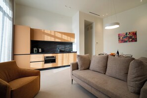 Ein modernes Wohnzimmer mit Sofa, Couchtisch und einer Küchenzeile mit Schränken und Arbeitsfläche.