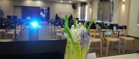 A conference room with rows of chairs, a podium, and a glass vase with flowers on a table.