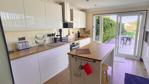 A modern kitchen with white cabinets, a wooden countertop, a built-in oven, and a sliding glass door leading to a patio.
