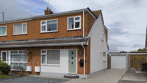 A two-story residential building with a front door, windows, and a satellite dish.