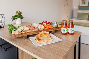 Et træbord med forskellig mad, blandt andet brød, ost og syltetøj.