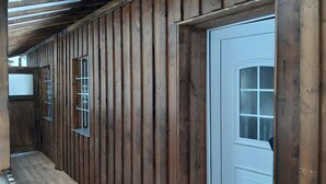 Puinen käytävä, jossa on valkoinen ovi ja ikkuna, jossa on metalliset säleet.