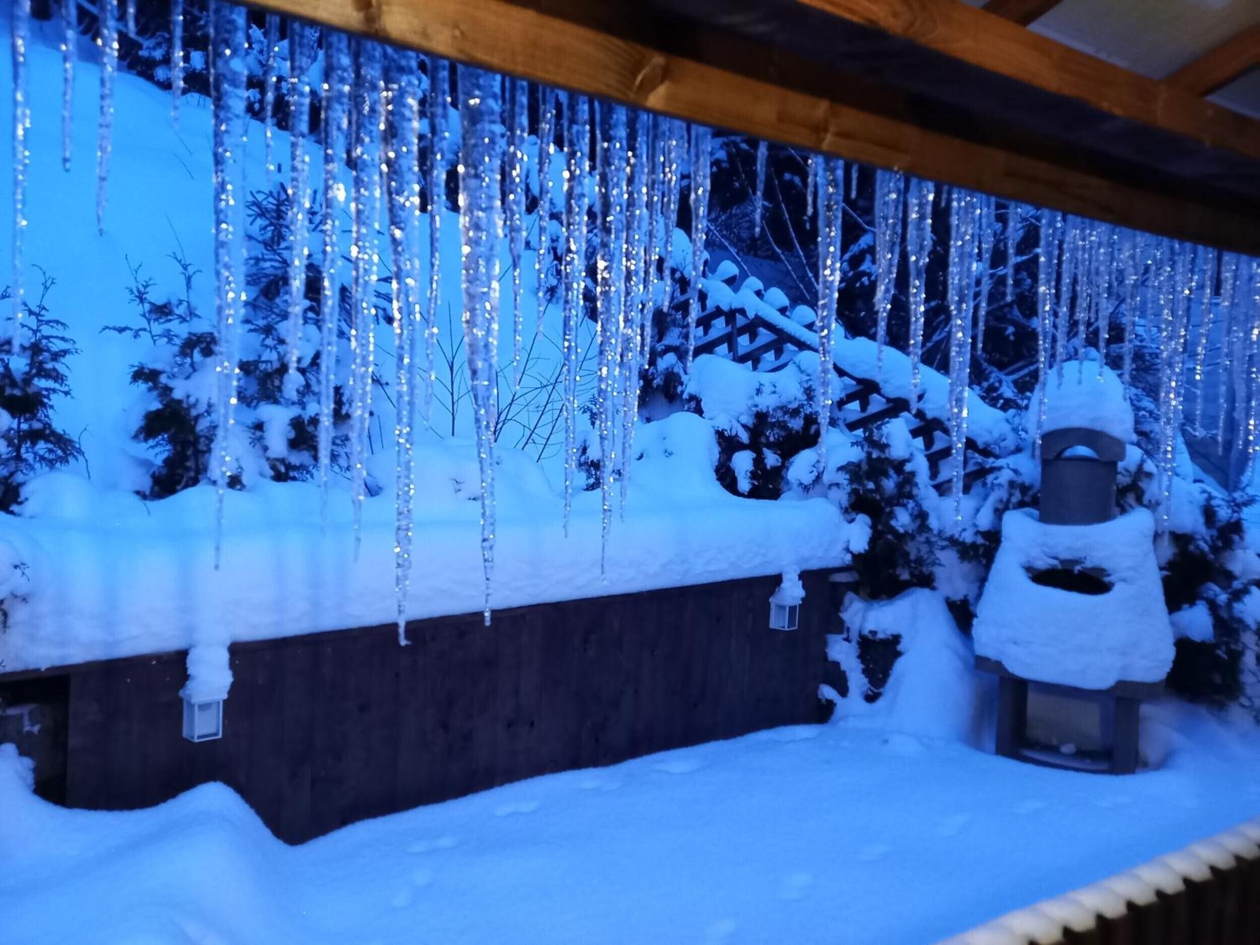 Ein verschneiter Außenbereich mit Eiszapfen von der Decke und einer Schneemann-Statue.