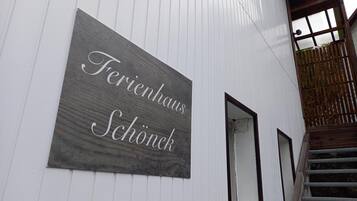 Ein Schild an einem weißen Gebäude mit dem Schriftzug 'Ferienhaus Schönek'.