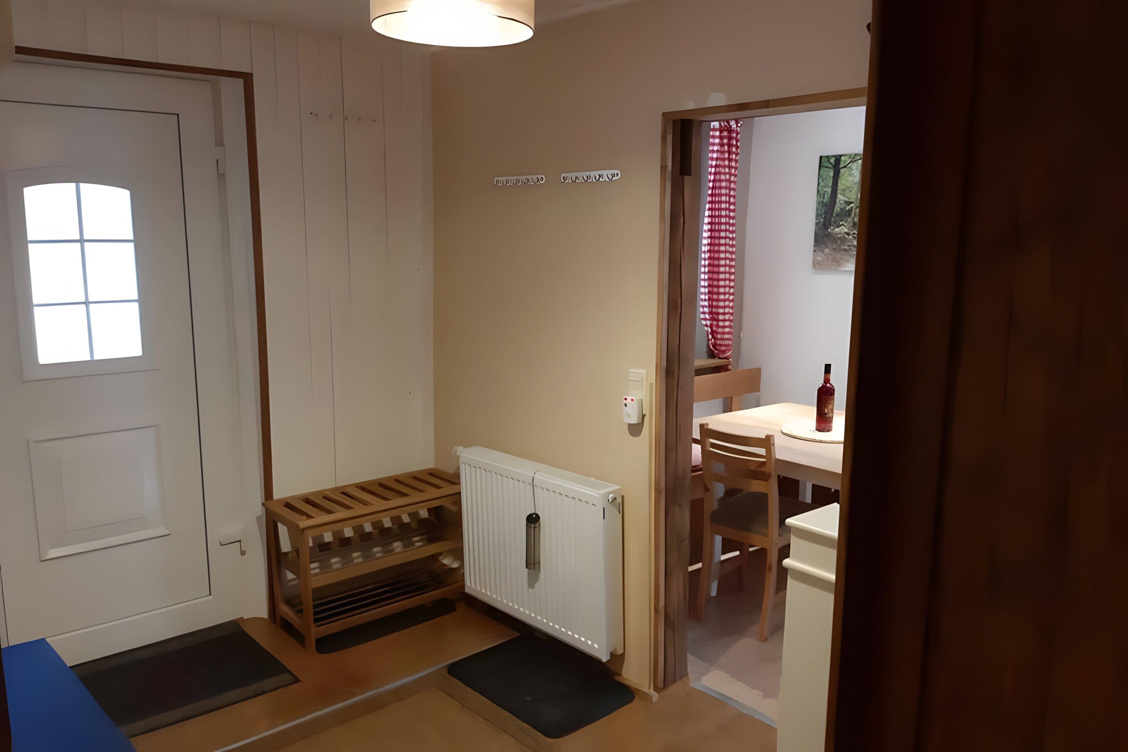 Une pièce avec un banc en bois, un radiateur, une petite table et une chaise.