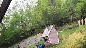 Pihalla on terassi, jossa on pöytä ja tuoleja, pieni varasto, liukumäki ja puinen terassilattia.