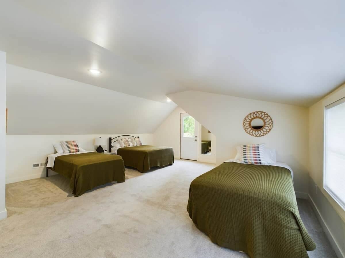 Una camera da letto con due letti singoli, un'ampia finestra e una porta che dà su un'altra stanza.
