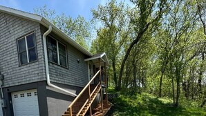 A two-story house with a covered porch and a set of wooden stairs leading to the entrance. - Cabin with private dock/beach access to Lake Minnewaska (Glenwood)