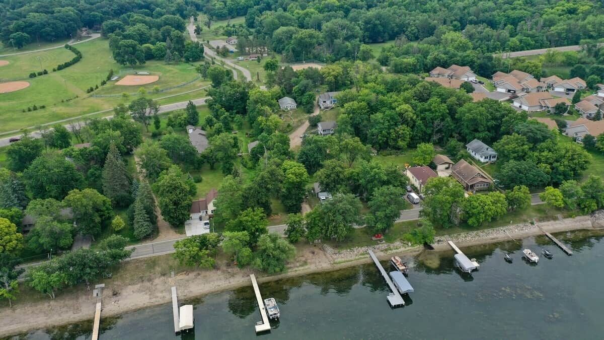Vue aérienne d’une communauté riveraine, avec des maisons, un terrain de baseball et des bateaux amarrés.