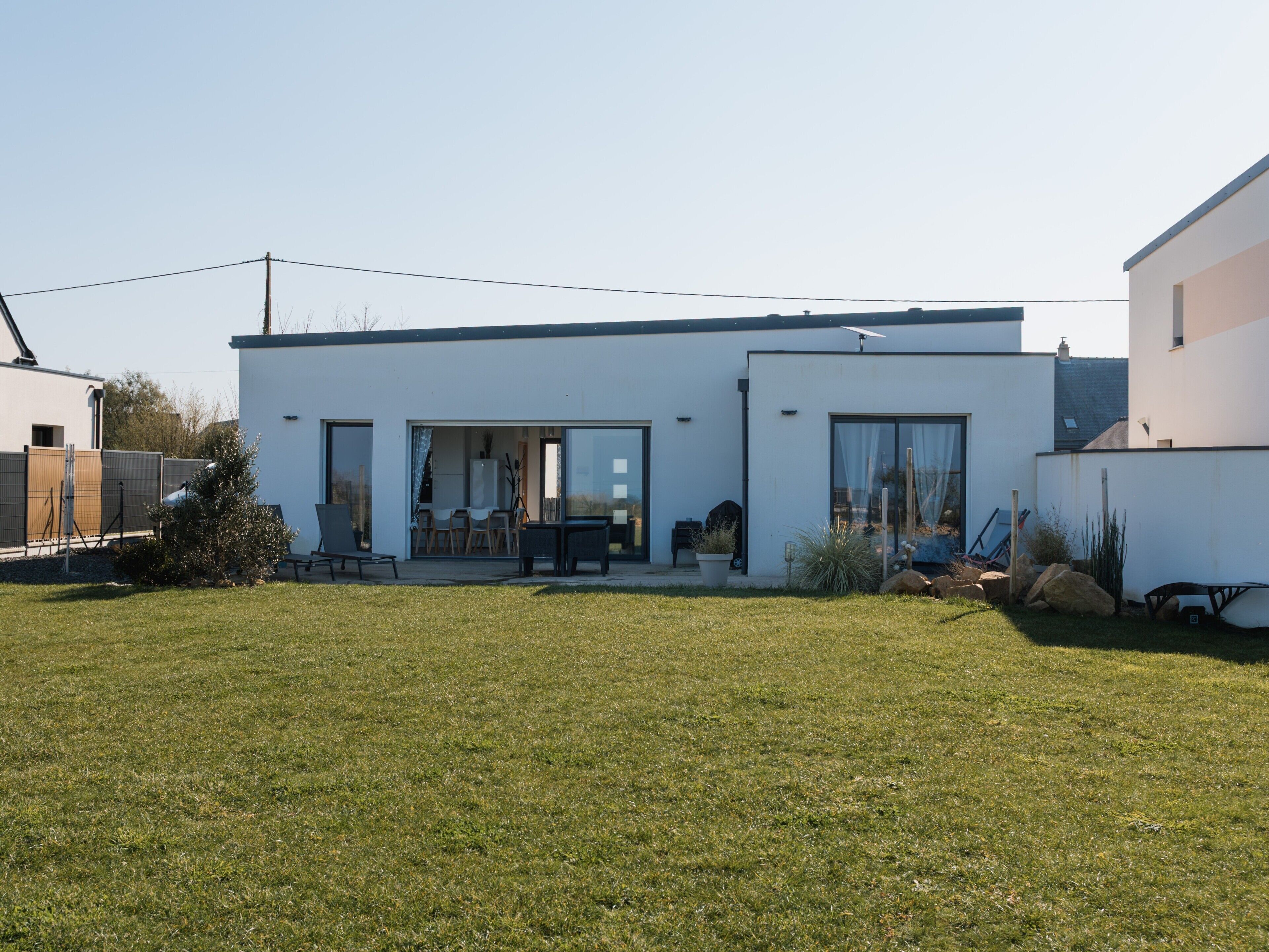 Une maison moderne dotée d’un patio, d’un coin repas et d’un garage.