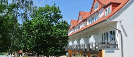 A building with a red-tiled roof, multiple windows, and a covered outdoor area with a railing.