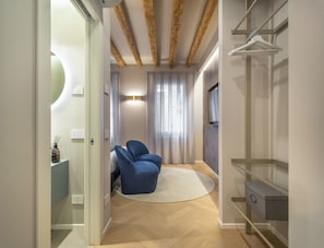 Ein modernes Schlafzimmer mit Holzboden, einem blauen Sessel, einem weißen Teppich und einem eingebauten Kleiderschrank.