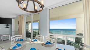Een eethoek met een tafel gedekt voor vier personen, met uitzicht op een strand.
