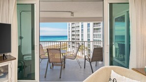 Ein Balkon mit Blick auf das Meer und ein Gebäude, ausgestattet mit Stühlen und einem Tisch.