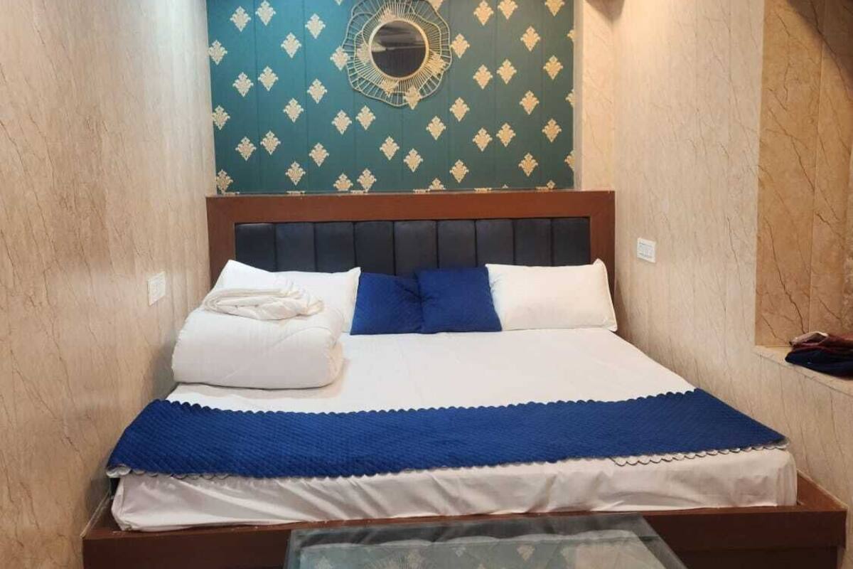 A bedroom with a bed, a ceiling fan, a decorative wall, and a glass table.