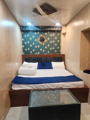Ein Schlafzimmer mit einem Bett, einem Deckenventilator, einer Wanddekoration und einem Glastisch.