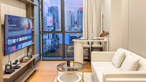 A modern living room with a large TV, a dining table, and a sofa. - Luxe City Condo in Central Bangkok · (Bangkok)