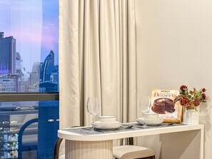Un coin repas avec une table dressée pour deux personnes, un livre de recettes de desserts et un vase rempli de fleurs.