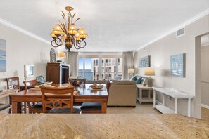Ein geräumiges Wohnzimmer mit Essbereich, einer Chandelüster und Blick auf den Balkon.