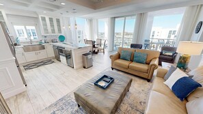 A spacious living area with a sofa, ottoman, and a dining table with chairs. - Stunning Penthouse 1125 w/Garage Space and Beach Svc for 2 (Destin)