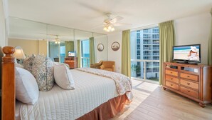 A hotel room with a large bed, a television, a dresser, and a balcony with a view of the city. - Perfect Beachfront Location ST 2054 (Destin)