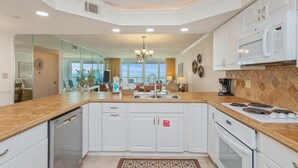A modern kitchen with white cabinetry, a central island, and a view to the outside. - Perfect Beachfront Location ST 2054 (Destin)