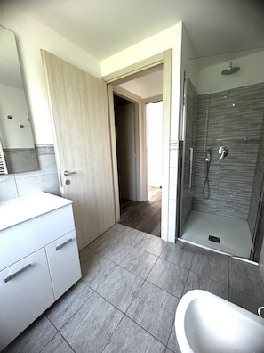 A modern bathroom with a shower, a toilet, and a sink. - Modern Family Flat With a Terrace (San Michele al Tagliamento)