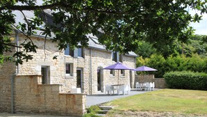 A stone building with a patio area featuring outdoor seating and umbrellas.