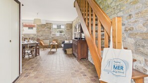 A cozy interior with a stone wall, wooden staircase, and a dining area with chairs and a table.
