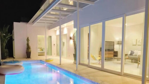 Ein modernes Haus mit Swimmingpool, großen Glasfenstern und einem gut beleuchteten Innenraum.