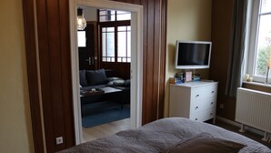 A bedroom with a bed, a television on a dresser, a radiator, and a window with curtains. - Apartment 'Harz Idylle 2' with Wi-Fi (Güntersberge)