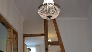Un escalier en bois, un lustre, un canapé rouge et une petite table avec une bougie.