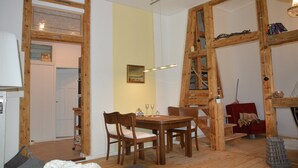 Un coin repas avec une table et des chaises en bois, un fauteuil rouge et une bibliothèque.